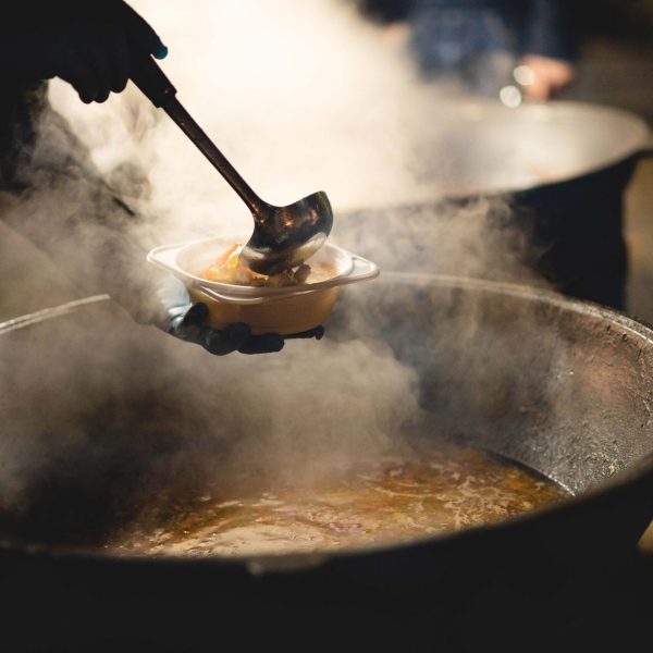 the cook fills a bowl with hot street food